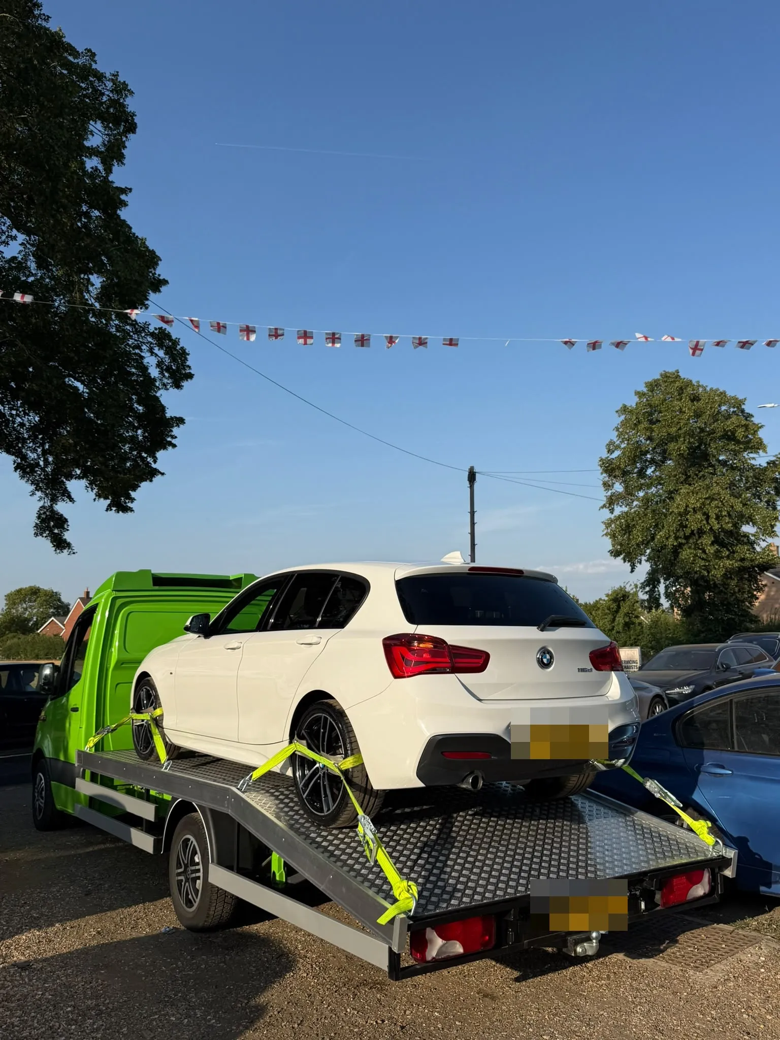 White BMW strapped on the flatbed under bunting