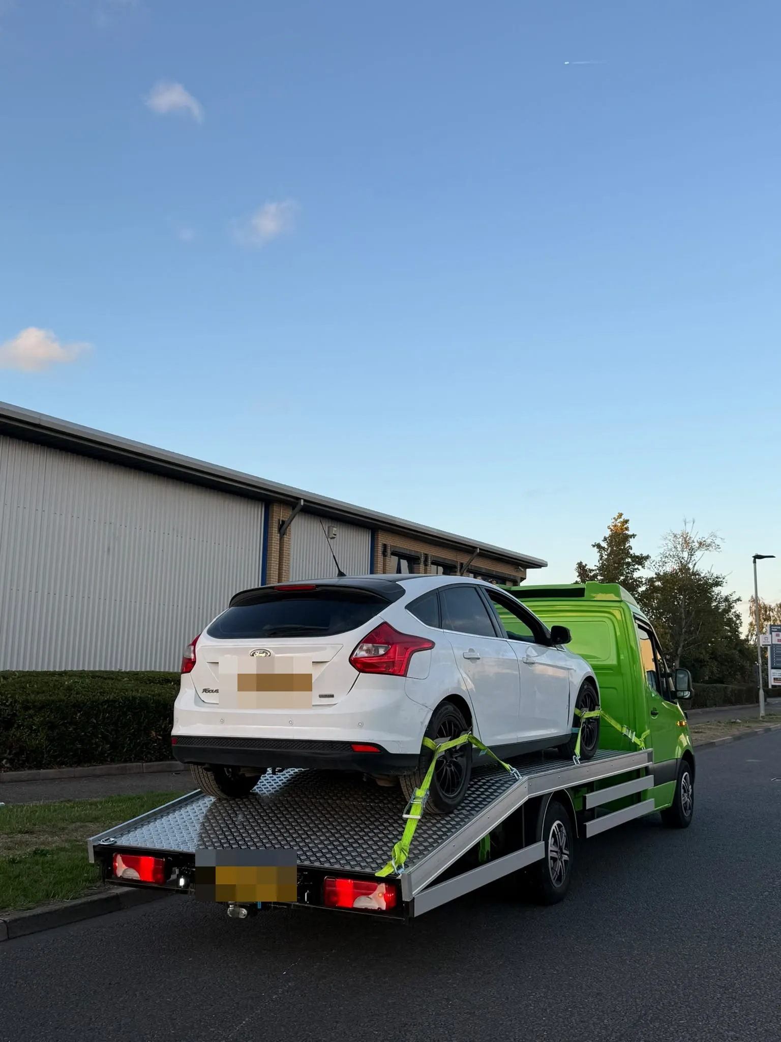White Ford Focus strapped on the flatbed at a business park