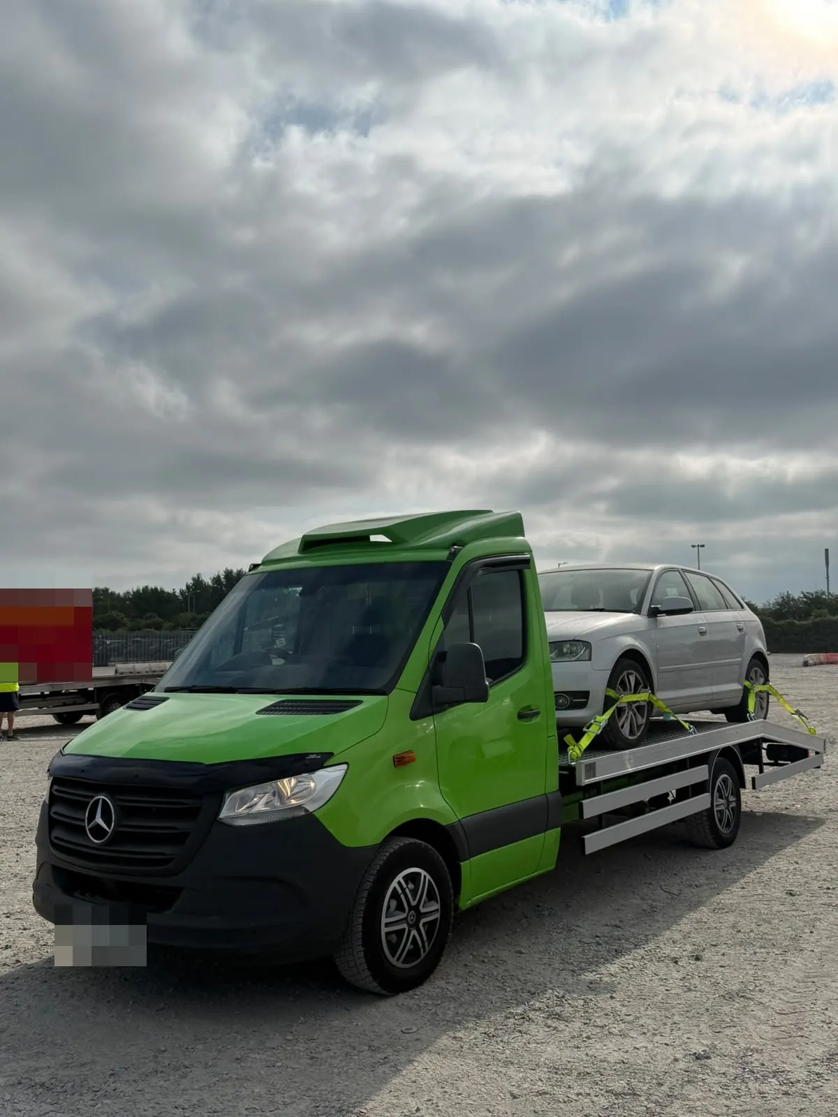 Front of the Sprinter flatbed with a silver Audi on board